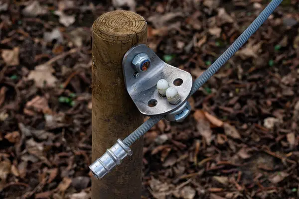 Sağlam bir metal kablo konnektörü tahta bir direğe bağlanır. Kalenin etrafında kuru yapraklardan oluşan bir yatak var. Bu da açık hava ortamını gösteriyor. Ayarlar bir işlevsel ya da eğlence alanı öneriyor.