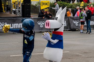 ALMANY, PADERBORN, 77 EASTER RUN, 04-19-2025. Şehirdeki bir topluluk etkinliği sırasında iki maskot kalabalığı eğlendiriyor. Biri mavi bir ayı ve diğeri de bir domuz. Sadece editör kullanımı.