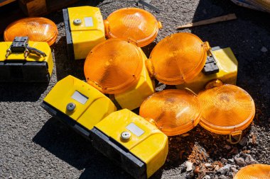 Sarı ve turuncu trafik ışıkları bir inşaat sahasına saçılmış durumda. Parlak renkler, gün içinde yakınlarda çalışma faaliyetlerinin sinyalini vererek ihtiyatı gösteriyor..
