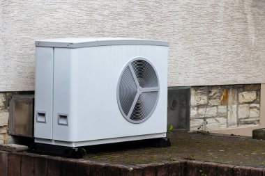 Sert bir yüzey üzerinde bir binanın dışında bir havalandırma ünitesi bulunmaktadır. Birim büyük bir pervane ızgarasına sahiptir ve dokulu yüzeylerle çevrilidir. Muhtemelen iç mekanı soğutmak için kullanılır..