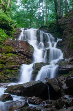 Ukrayna 'nın Karpat Dağları' ndaki Shypit Şelalesi 'nin çarpıcı uzun pozlama fotoğrafı. Uzun pozlama tekniği, çağlayan su üzerinde yosunlu kayalar ve yemyeşil orman ile güzel tezat oluşturan yumuşak ve ipeksi bir etki yaratır. 