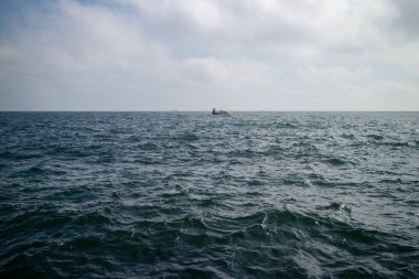 Odesa Ukrayna yakınlarındaki Karadeniz 'in açık sularında tek bir balıkçı teknesi görülür. Uzak ufuk çizgisine uzanan ince dalgalar, sakin ve sınırsız bir okyanus hissi taşır..