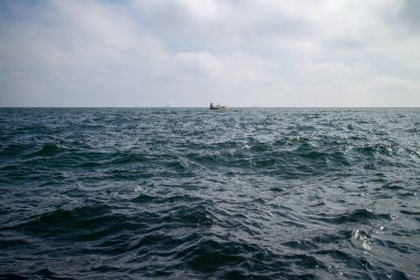 Odesa Ukrayna yakınlarındaki Karadeniz 'in açık sularında tek bir balıkçı teknesi görülür. Uzak ufuk çizgisine uzanan ince dalgalar, sakin ve sınırsız bir okyanus hissi taşır..