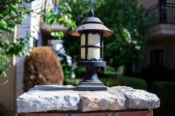 Old vintage street lamp on top of brick fence at the garden. Metallic street lantern retro style. Street lightning.