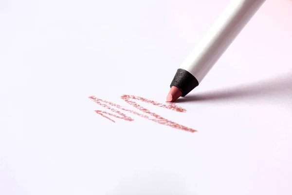 Cosmetic pencil and stroke isolated on white. Make-up pencil red strokes on white paper. Macro photo