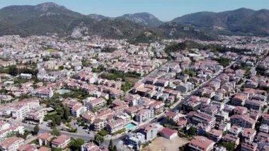 Mugla ilinin Marmaris tatil beldesi Cityscape 'in hava aracı görüntüsü. Deniz kıyısında dağlarla çevrili bir turist kasabası. Arabalar kavşaktan geçiyor