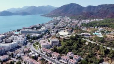 Türkiye 'de kalabalık plajlı, güneşli bir Marmaris şehrinin havadan görünüşü. Mavi deniz yüzeyinde tekne izleri var. Beyaz kumlu kumsal manzarası.