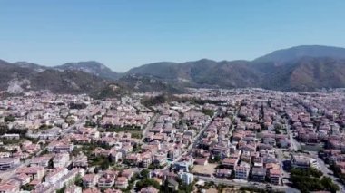 Mugla ilinin Marmaris tatil beldesi Cityscape 'in hava aracı görüntüsü. Deniz kıyısında dağlarla çevrili bir turist kasabası. Marmaris üzerindeki Türk bayrağına İHA bakışı.