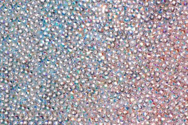 Abstract rhinestones background. Texture of rhinestones illuminated with multi-colored light. Pink and blue shine diamonds. Close up. Flares on glass.