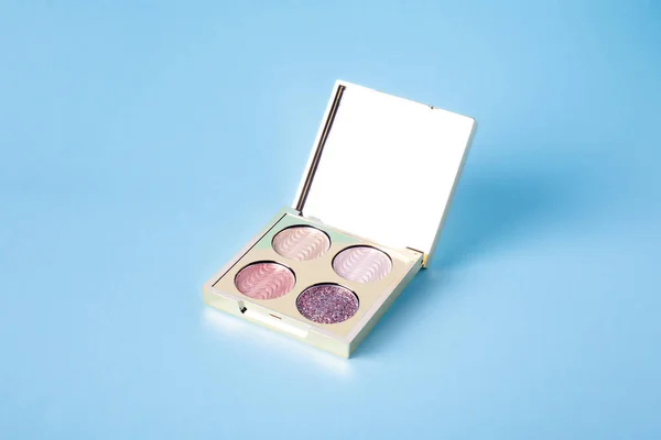 Eyeshadow palette for make-up on blue background. Classic Eyeshadow palette with facial mirror. pastel eyeshadows