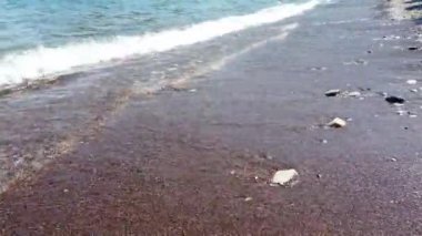 Clearwater Sahili 'nin yakınındaki çakıl taşlı sahil şeridine yumuşak dalgalar çarpıyor. Güneşli sahilden gelen deniz dalgaları. Temiz deniz suyu