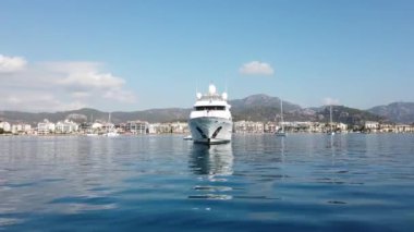 White modern yacht moored near Marmaris city in Turkey. Luxury white boat yacht on the background of the resort city. Ships in sea. Sea traveling. View from boat. Marmaris, Turkey - September 8, 2022.