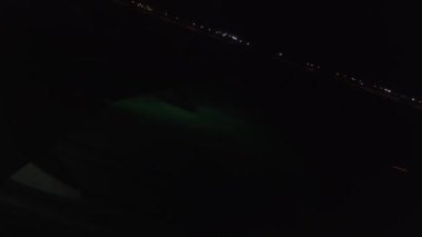 Uçak taksiden iniyor. Uçak kanadındaki ışıkların uçak penceresinden bak. Uçak kalkıyor ve tırmanıyor. Gece videosu.