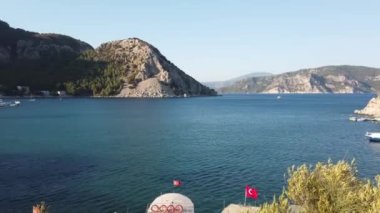 Turunc adlı küçük bir turistik köyde dağlarla ve kayalarla çevrili bir sahil. Zevk yatıyla demirlenmiş manzara. Panoramik manzara. Türkiye, Turunc - 5 Eylül 2021