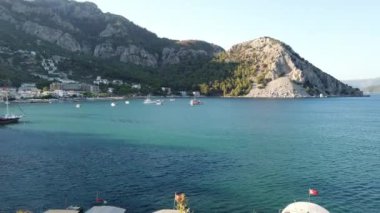 Turunc adlı küçük bir turistik köyde dağlarla ve kayalarla çevrili bir sahil. Zevk yatıyla demirlenmiş manzara. Panoramik manzara. Türkiye, Turunc - 5 Eylül 2021