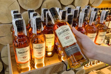 Hand holding Oakheart spiced rum Bacardi 500 ml rum bottle in a supermarket shelf closeup. Ukraine, Kharkiv - july 20, 2023
