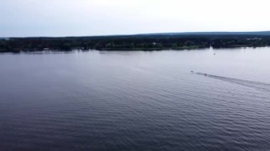 Bir sürat teknesinin havası nehir kıyısında bir muz teknesini çekiyor. Göl kıyısında şişme cazibe.