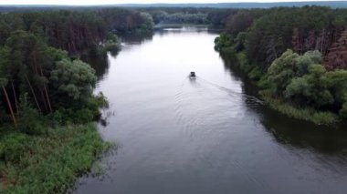 Motorlu tekne ve sakin suda yol alan havadan nehre. Motorlu tekne ormanın içinden nehirde ilerliyor.