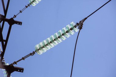 Yüksek voltajlı cam yalıtkan elektrik hattı mavi gökyüzüne yakın..
