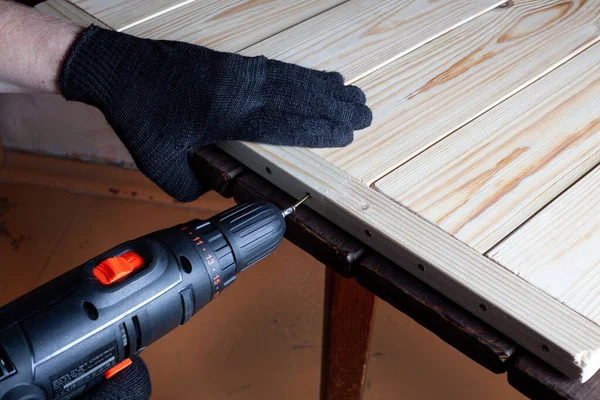 Carpentry work. The self-tapping screw is screwed into a wooden beam. Furniture assembly
