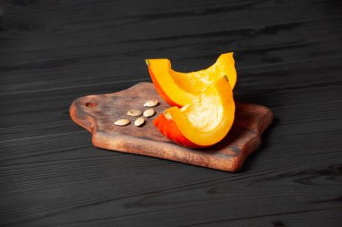 Koyu ahşap arka planda dilimlenmiş balkabağı. Masada kırmızı balkabağı.