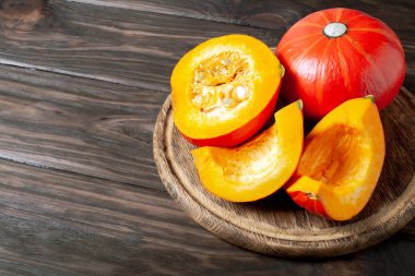 Koyu ahşap arka planda dilimlenmiş balkabağı. Masada kırmızı balkabağı.