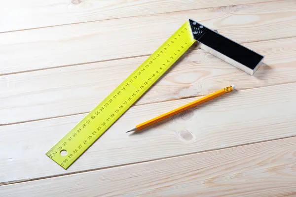Square ruler and pencil for measuring on wooden board. construction concept. Close up