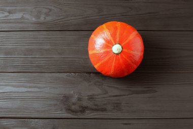 Koyu ahşap arka planda turuncu balkabağı. Masada kırmızı balkabağı.