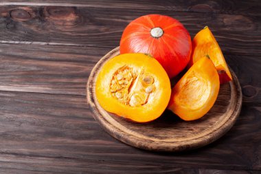 Koyu ahşap arka planda dilimlenmiş balkabağı. Masada kırmızı balkabağı.