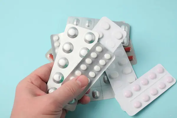 A female hand holds a package of pills. Pills blister in the hand