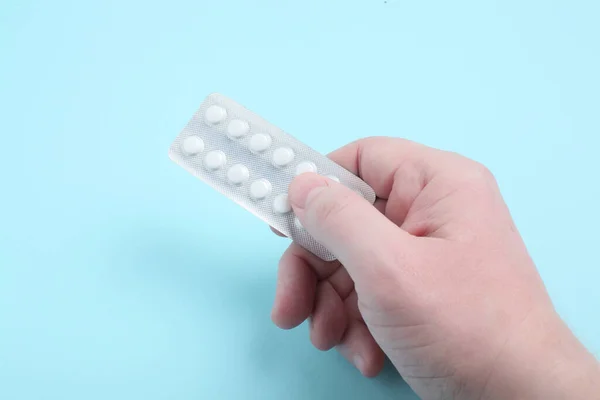A male hand holds a package of pills. Pills blister in the hand