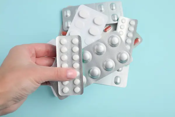 A female hand holds a package of pills. Pills blister in the hand. self-medication concept