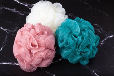 Küresel polyester banyo süngerleri siyah mermer yüzeyde. Rahatça banyo yapmak..