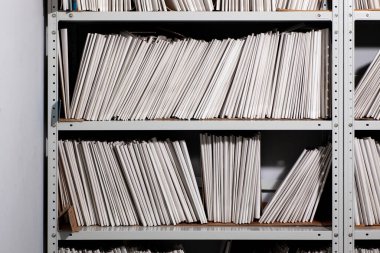 Kağıt belgelerle dolu raflar. Düzenli düzenlenmiş kağıt belgeleri ve dosya dolapları olan düzenli ofis alanı.
