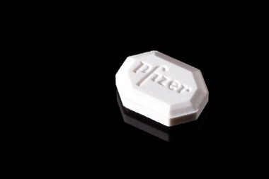 Siyah arkaplan üzerine beyaz Pfizer tableti yakın plan. Modern ilaç endüstrisini resmediyor. Kharkiv, Ukrayna - 18 Kasım 2023