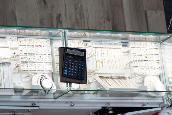 Kolyeler, yüzükler ve bir kuyumcuda hesap makinesi olan mücevher dolabı.