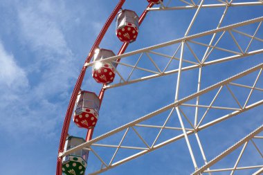 Mavi gökyüzüne karşı parlak dönme dolaplar, eğlence parkı dolu bir günün özünü yakalıyor.