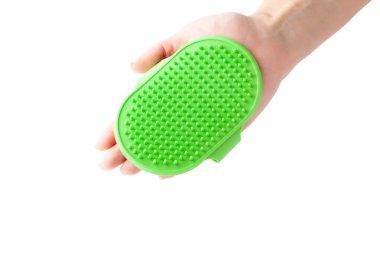 Beyaz arka planda yeşil silikon bir hayvan tımarlama fırçası tutuyor.