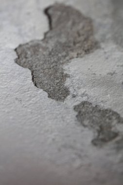 Hasarlı alçılı eski beyaz duvar. Arka plandaki binaları kapatıyor. Çimentoyu paramparça ediyor.