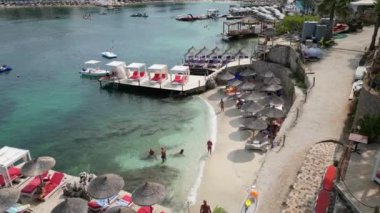 Arnavutluk 'un Ksamil kenti, 12 Ağustos 2023. Güzel 3 ada kristal sularıyla mavi lagünü keşfediyor. Hava aracı görüntülerine göre yaz mevsimi, yüksek kaliteli sinematografi klipleri olabilmek için harika yerlere seyahat ediyor.