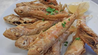 Piyasadaki buz tepsilerinde üst üste dizilmiş taze kırmızı kefal balıkları. Arka planda yüksek kalitede yükleme izleri.