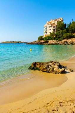 Apartment building on the beach of Ses Illetes, and the island of Sa Caleta in the background, Mallorca, Spain