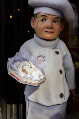 Palma, Mallorca, Balear Adaları, İspanya. 21 Temmuz 2022 - Sokaktaki ünlü bir pastanenin girişinde turistleri çekmek için tipik bir Mallorcan ensaimada tutan bir pasta şefi figürü