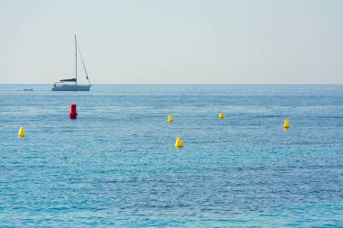 Mallorca 'da Illetes sahilinde yelken açan yelkenli, sudaki şamandıralarla.