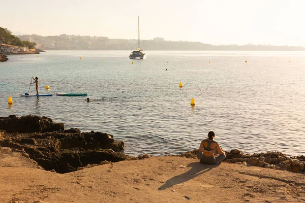Ses Iletes Majorca Balearic Islands スペイン 2022年7月22日 カタマランと人々はCala Comtesa入り江の岩の海岸近くでパドルサーフィンをしています ロイヤリティフリーのストック写真