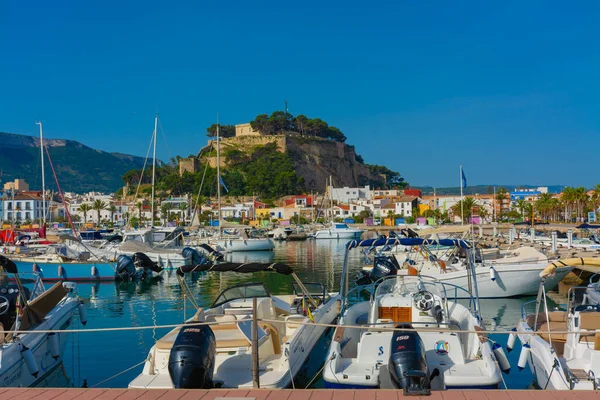 Denia, Alicante, İspanya. 22 Mayıs 2022 'de yelkenliler ve limana demirlemiş diğer tekneler. Arka planda, eski kasabadaki oteller ve restoranlar ve tepenin üstündeki şato.
