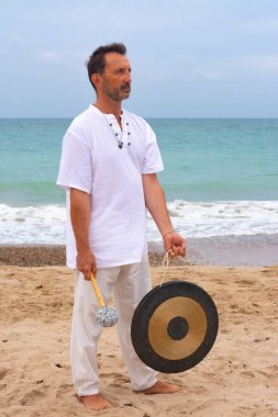 Meditasyon ve kumsalda kundalini yoga gongu yapan bir adam.
