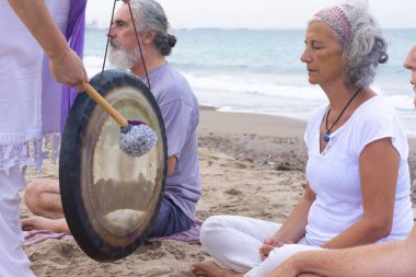 Kundalini yogası ve kumsalda gong temizleme ritüeli.