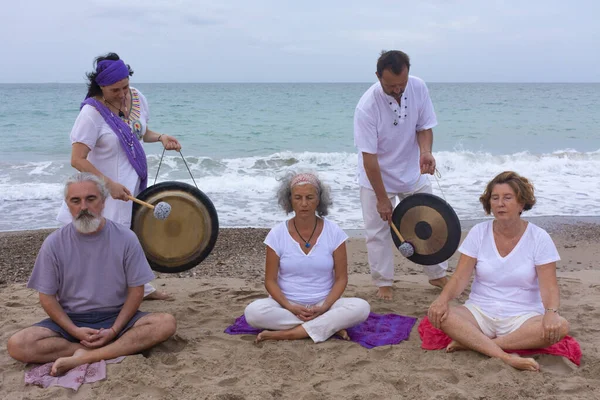Man and woman in a cleansing ritual kundalini with a gong in the beach