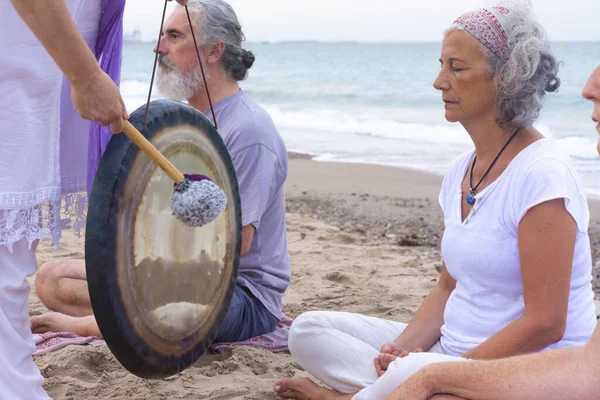 海滩上用Gong清洁传统的昆达里尼瑜伽 免版税图库图片